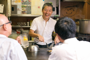 鉄板の前で、お客様と楽しく会話しながら広島お好み焼きを焼く、弘々家店長市山